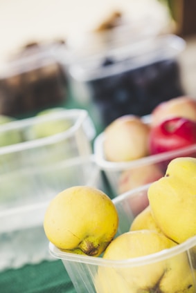 A vibrant assortment of fresh fruit pulps in clear containers on a rustic wooden table.