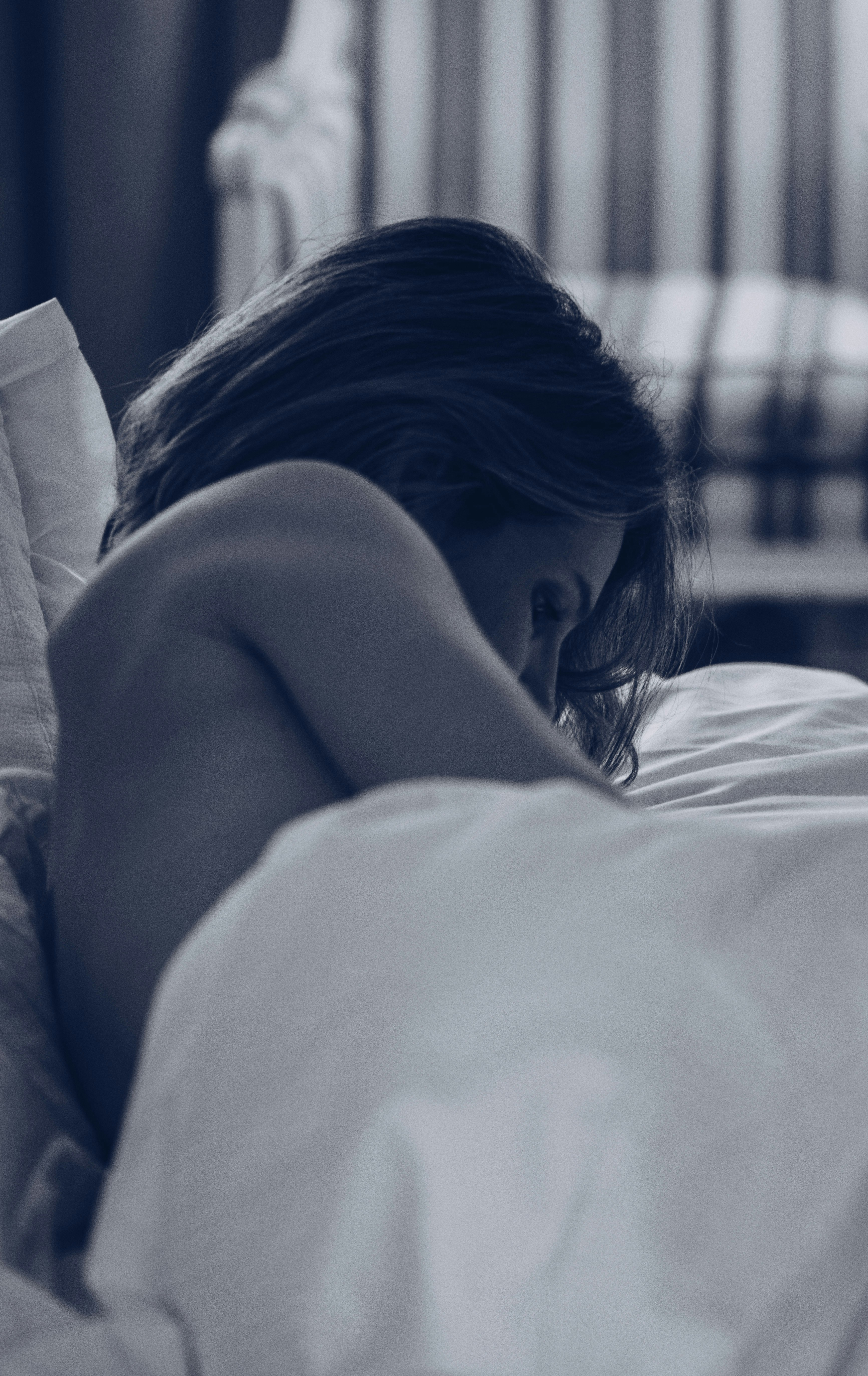 grayscale photography of woman lying in bed