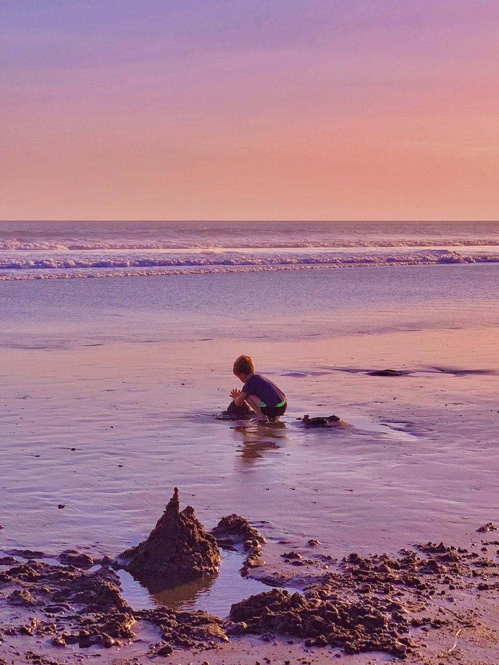 boy sitting on sea water at daytime