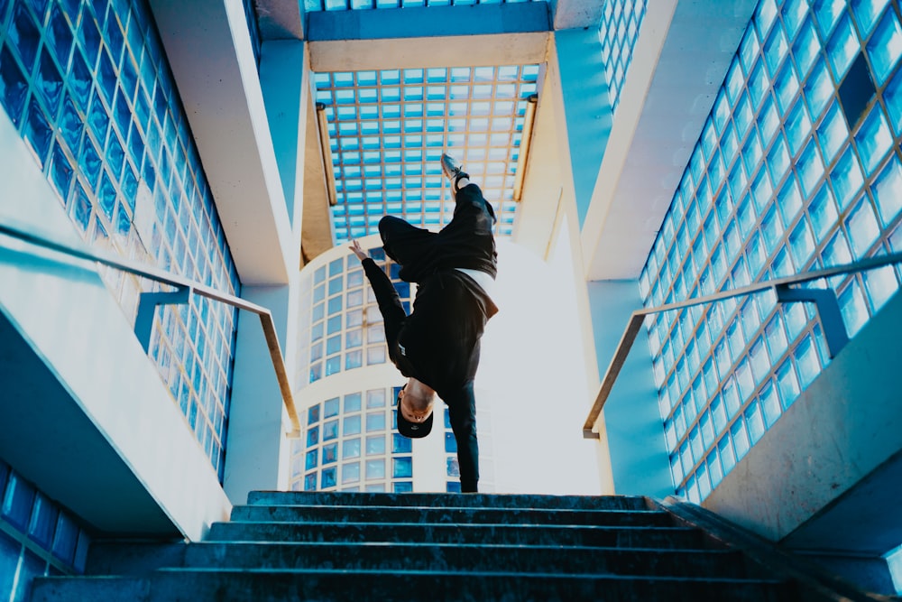 man balancing on one hand on top of the stairs during day