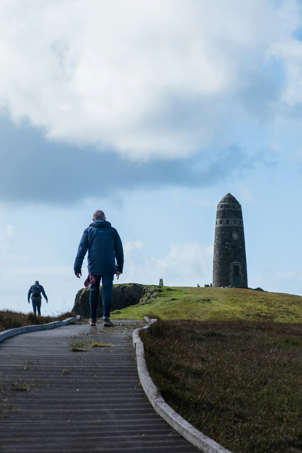 two people walking up a path towards a tower