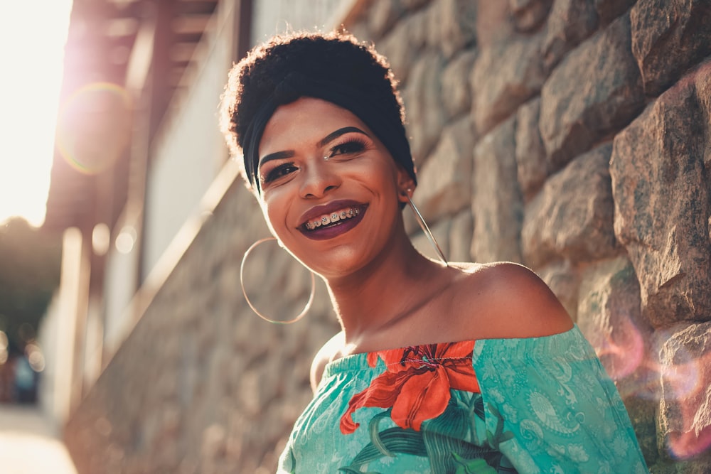 smiling woman leaning on brick wall