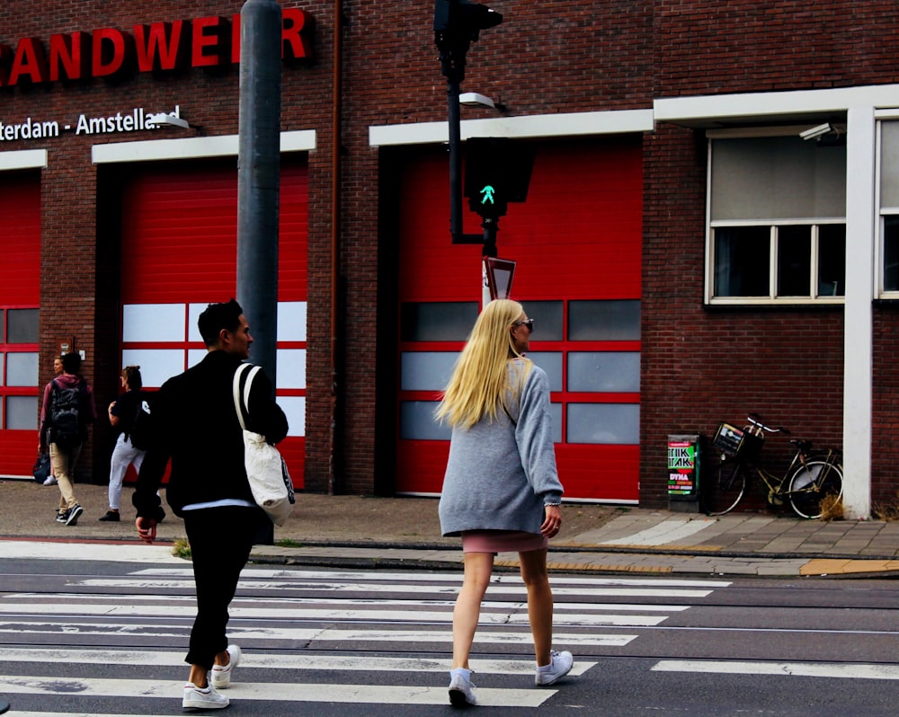 man and woman walking near red building