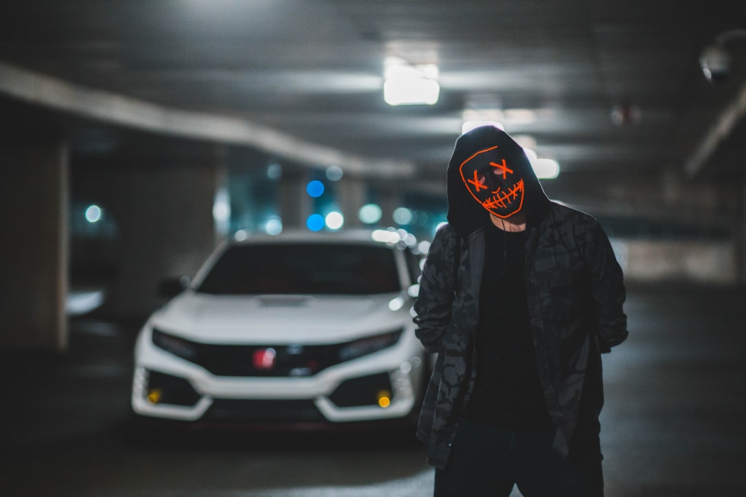 person in black hoodie wearing black and orange mask