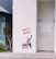 A stencil art piece on a white wall depicts a child holding up a red heart. Next to the child is a basket filled with more red hearts. The words 'HAVE A HEART' are written above in bold red letters. There are plants nearby on the left, adding some greenery beside the artwork. The setting appears to be an urban environment.