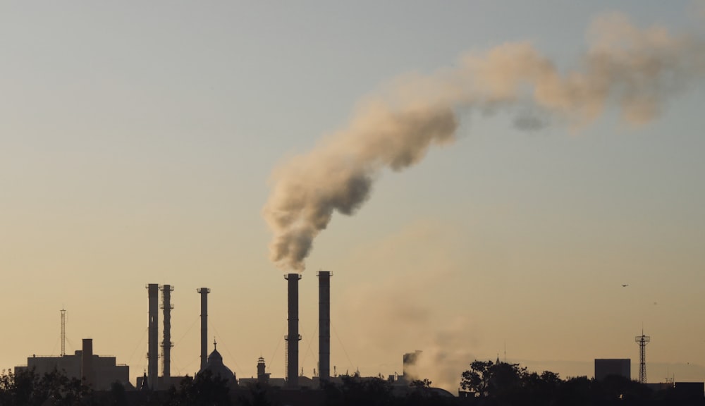 Una ciminiera emette da una fabbrica in lontananza