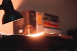 A bright desk lamp illuminating a study area with textbooks and a laptop.