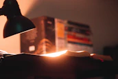A calm reading nook with a stack of AI books and a glowing desk lamp.