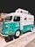 A colorful vintage food truck with a teal and white design, featuring the brand name 'NUTRILOVERS' and decorative graphics of hearts and fish. The front part of the truck showcases a distinctive logo, and the vehicle is parked on a paved area next to another truck.
