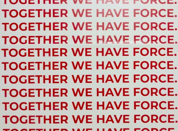A repeated phrase in bold red capital letters on a white background says 'TOGETHER WE HAVE FORCE.' The words are aligned and occupy the entire visual space in rows.