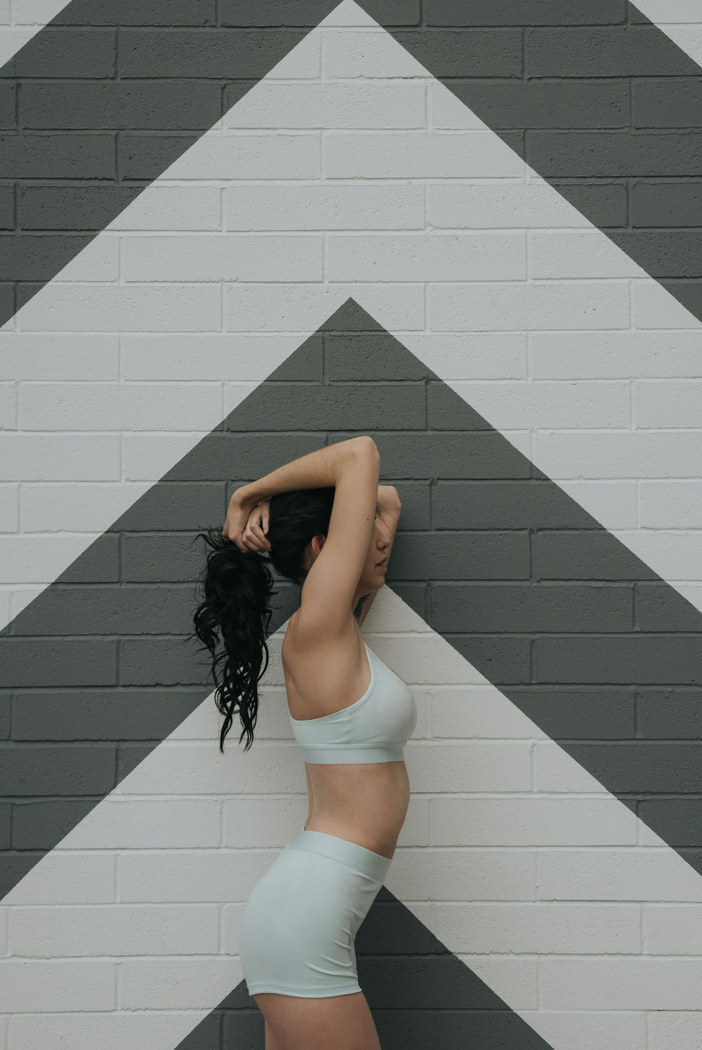 woman standing beside brick wall