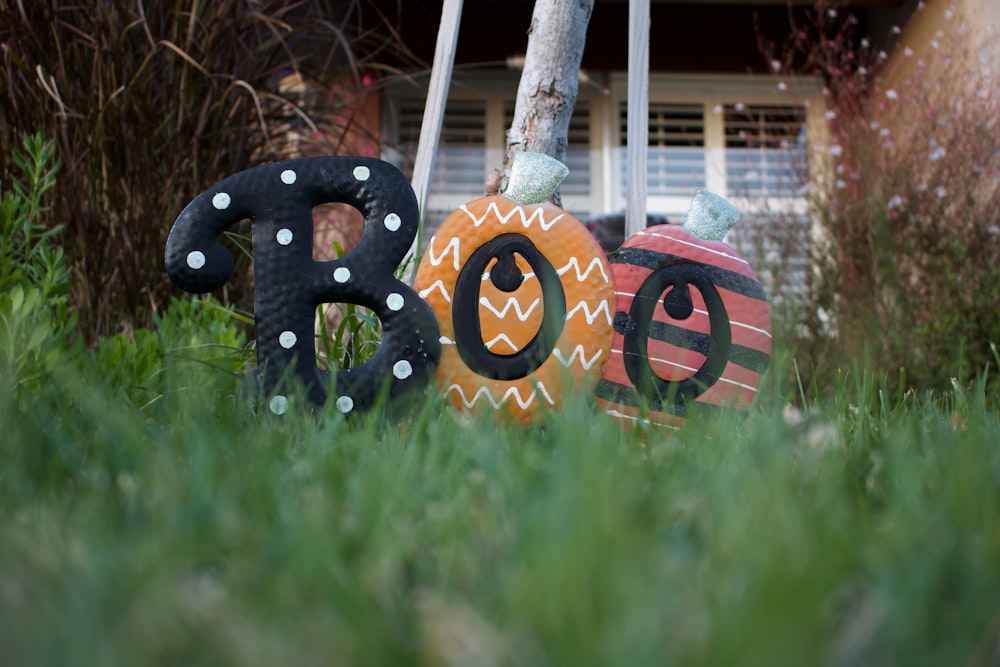 three assorted-color boo ornaments on grass
