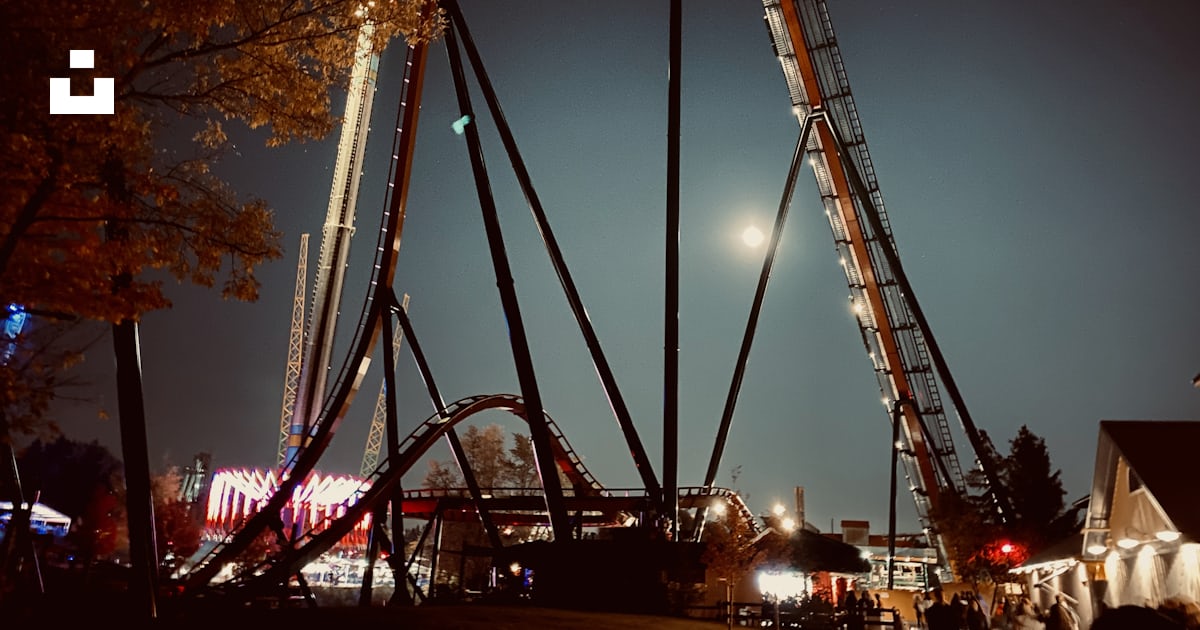 A roller coaster at night with a full moon in the background photo ...