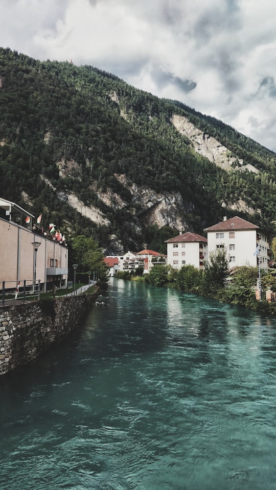 houses and buildings near body of water viewing mountain under white and blue sky during daytime in Interlaken Switzerland