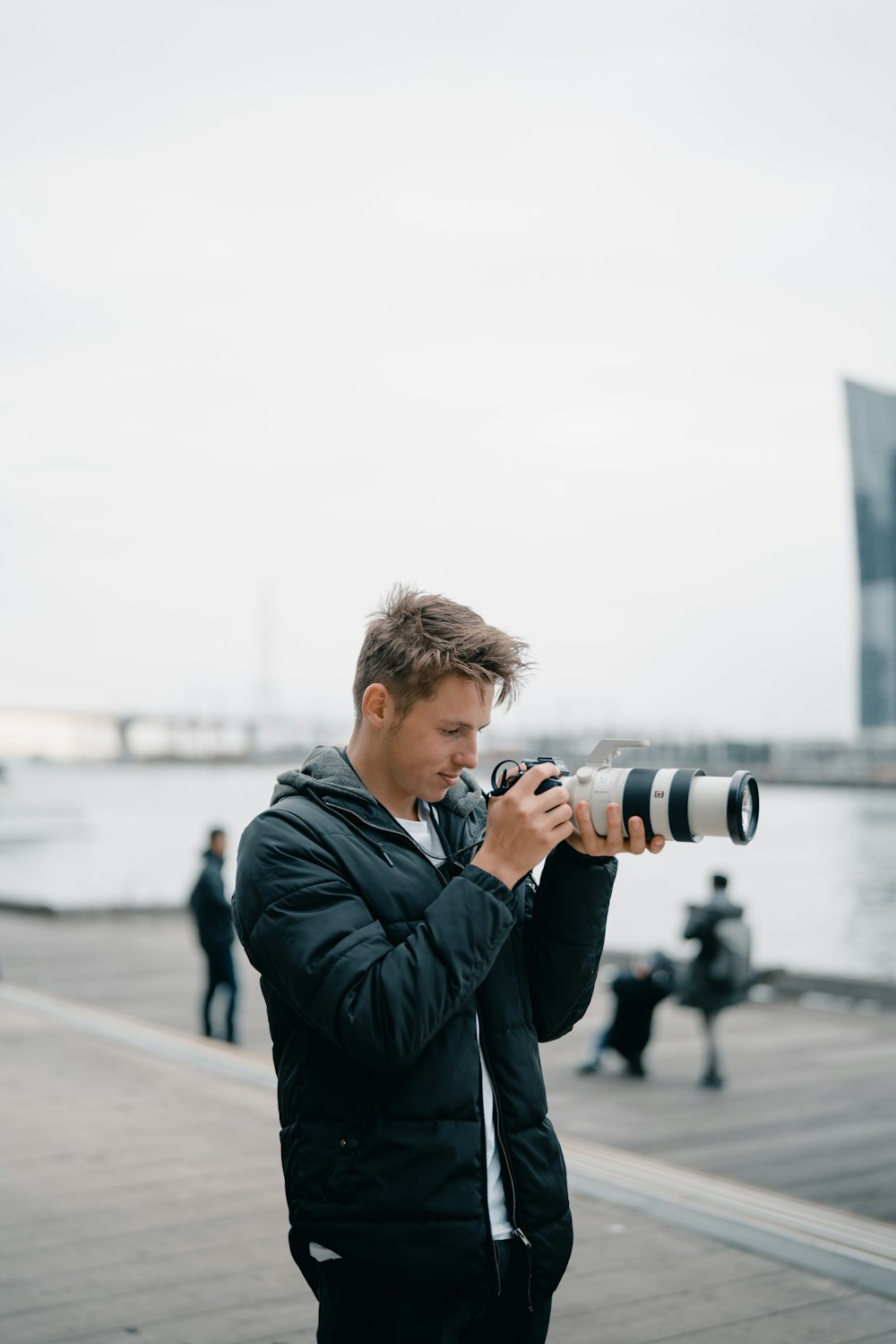 hombre sosteniendo una cámara DSLR negra al aire libre