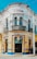 A vibrant, ornately designed corner building with intricate decorative elements, featuring a white and yellow façade accented with blue trim. The structure contains multiple arched windows and doors, with the name 'M RASCON' displayed prominently near the top. A sign for 'Funerales Puebla' is visible above one entrance, suggesting a funeral service establishment.
