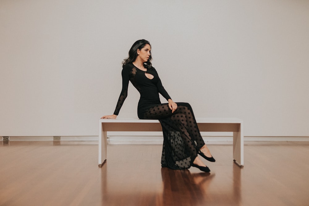 Frau im schwarzen Kleid sitzt auf Bank