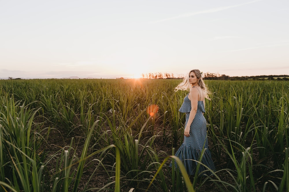 shallow focus photo of woman in blue spaghetti strap dress on grass field