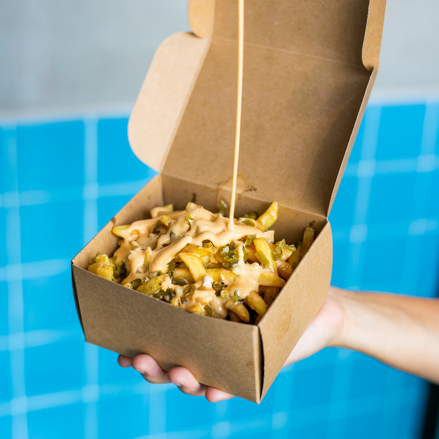 Frites dorées servies dans une barquette en carton à emporter