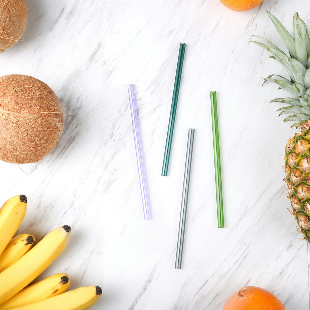 four assorted-color straws beside fruits