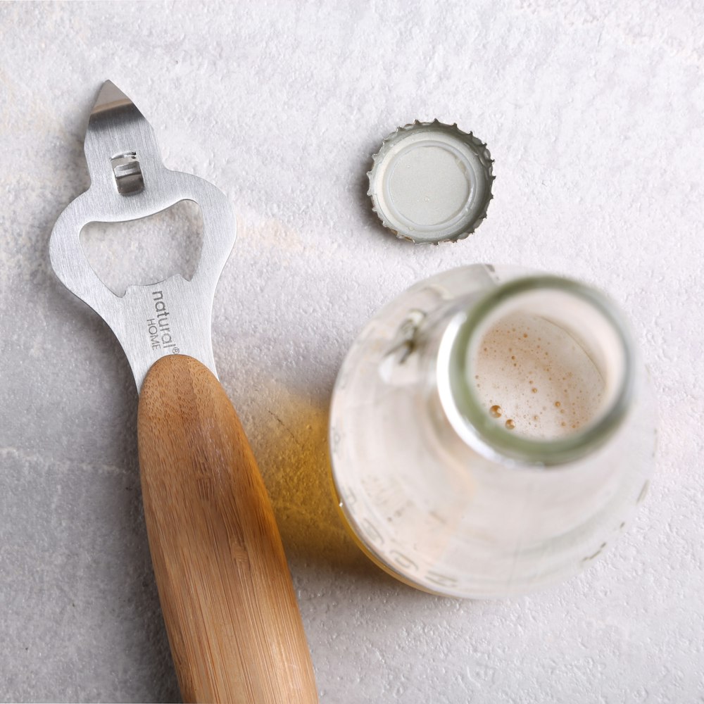 abridor de botellas gris al lado de la botella abierta