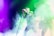 A performer is singing energetically on stage surrounded by vibrant colored lights and thick smoke. The atmosphere is lively and immersive, with the lights creating a dynamic backdrop. Another person appears to be playing a guitar, adding to the musical ambiance.
