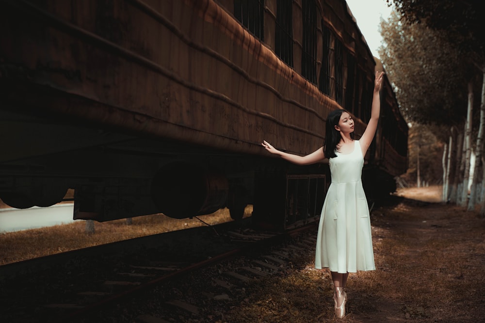 woman wearing white dress dancing beside train