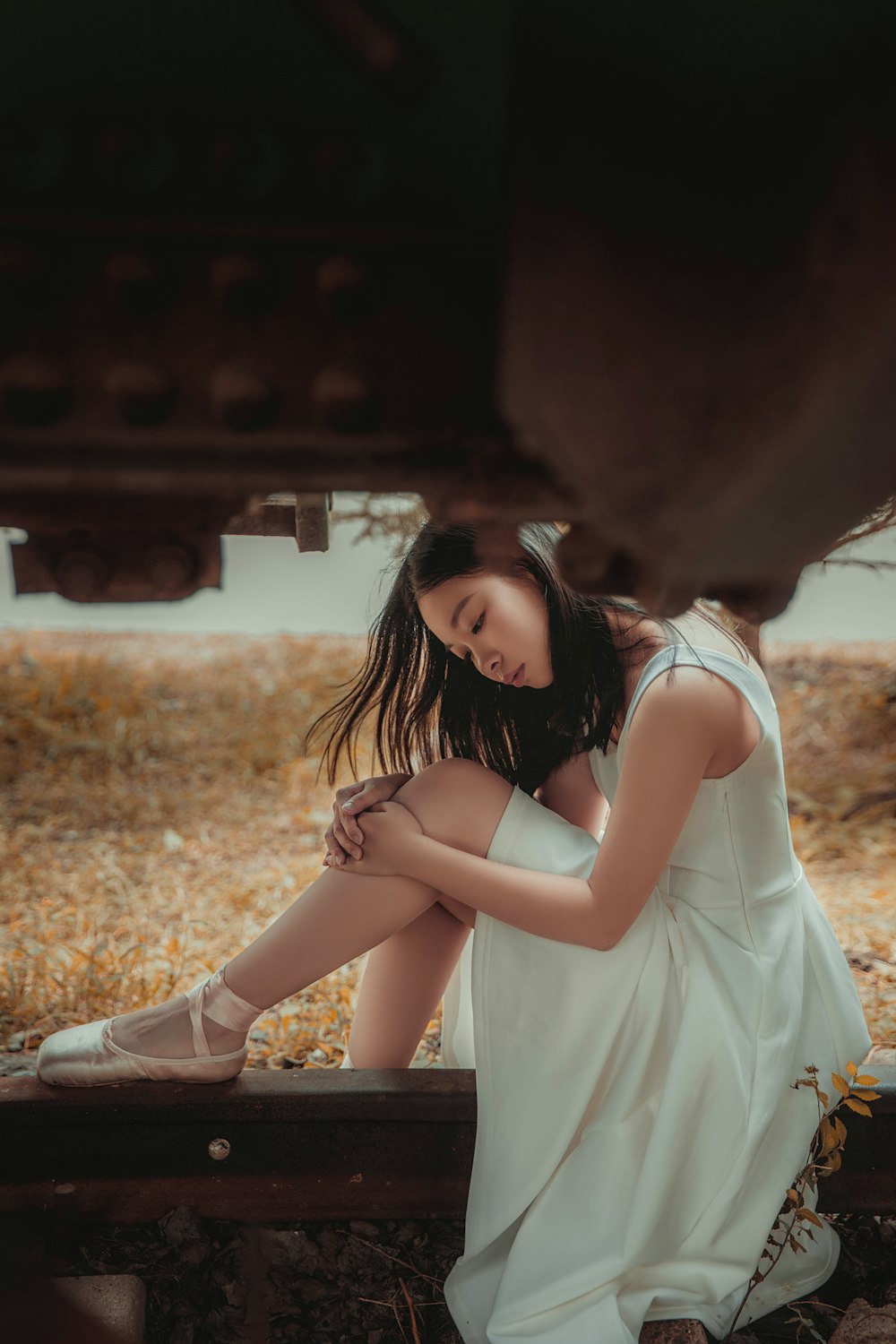 woman in white dress sitting under train