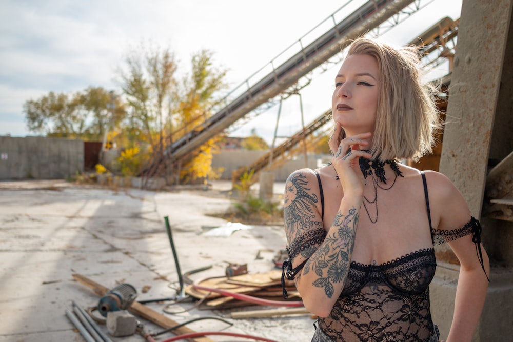 a woman with tattoos standing next to a pile of junk