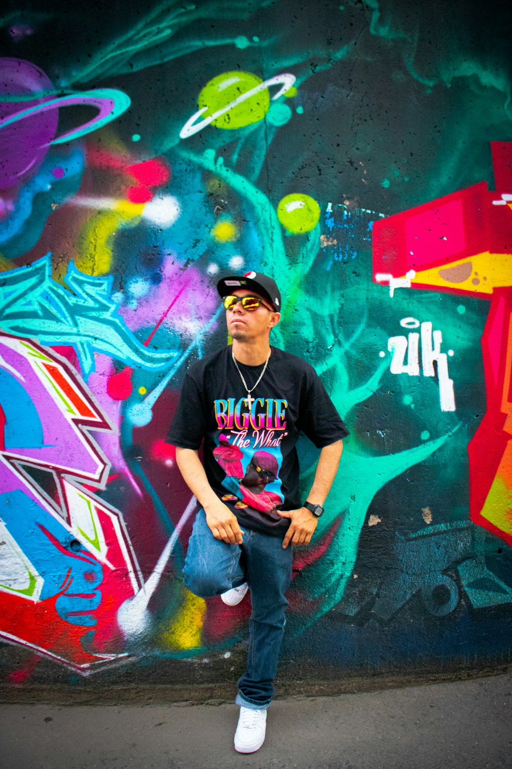 man leaning on graffiti wall