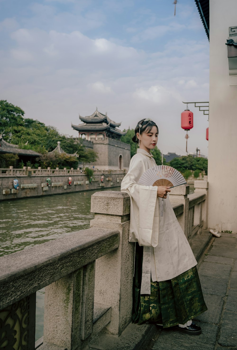 a woman in a traditional chinese dress holding a fan