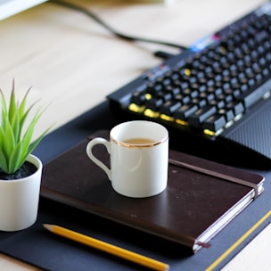 A calm office workspace with a notebook, pen, and a cup of coffee.
