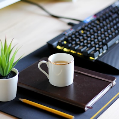 A clean office desk featuring blue and purple branded stationery and a coffee cup.