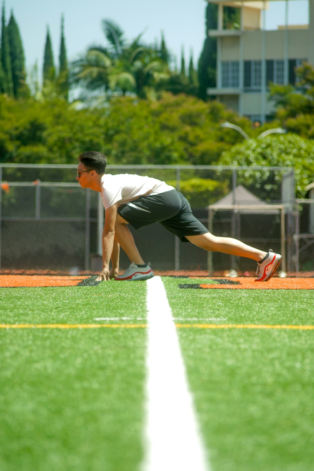 man on grass getting ready to run during day