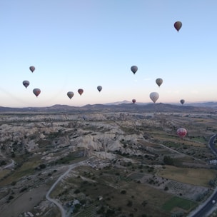 Hot air balloon flying over Cappadocia landscapes.