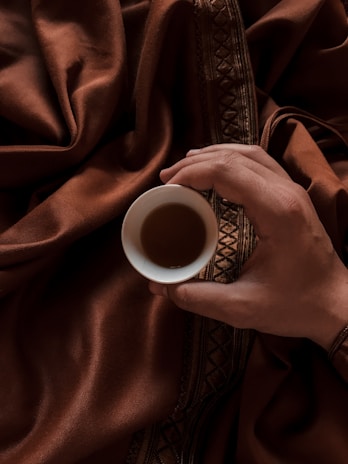 A close-up of a traveler’s hands holding a steaming cup of South Indian filter coffee.
