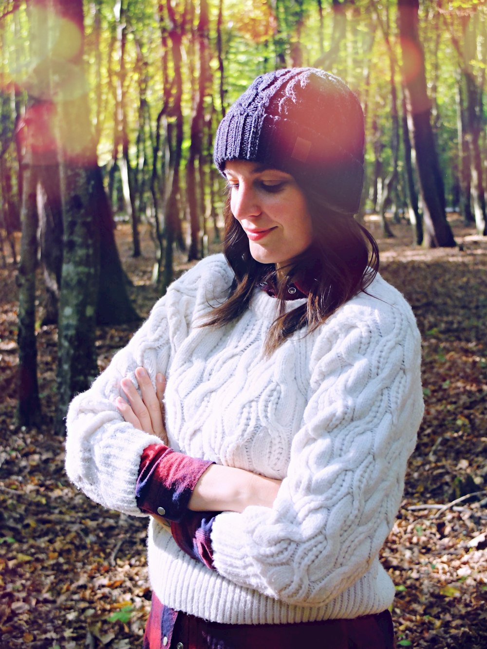 crossed arm smiling woman standing near trees