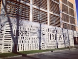 A modern building facade prominently features the word 'library' in multiple languages, artistically integrated into the design. The structure has a grid-like pattern of windows and shutters.