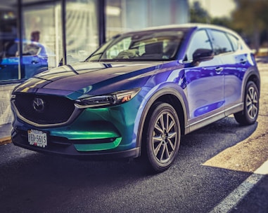 A shiny brand-new SUV parked in front of a modern showroom under bright daylight.