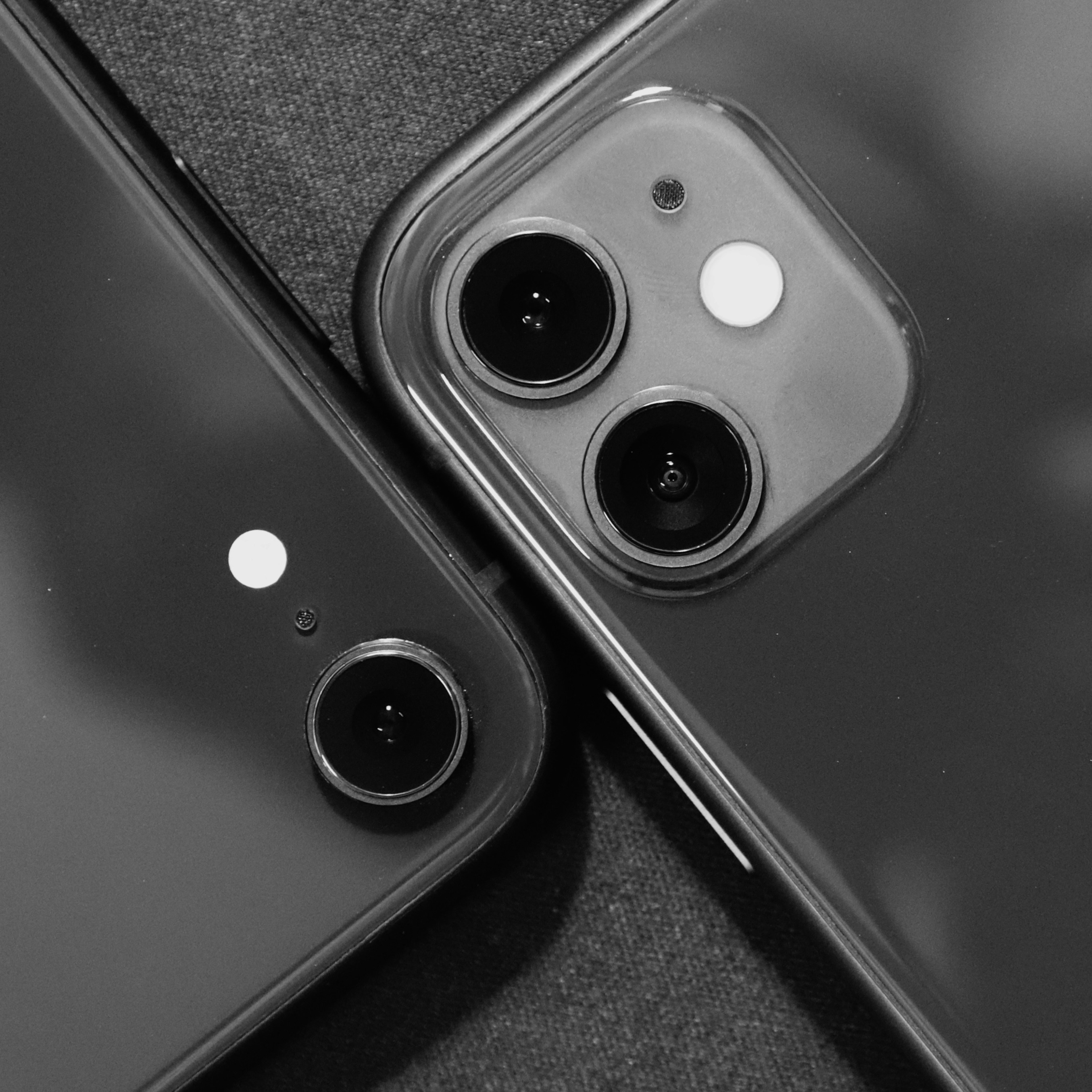 Dark studio flat lay of smartphones on matte black surface with dramatic side lighting