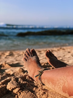 Elegant silver anklet with small beads resting on a sandy beach