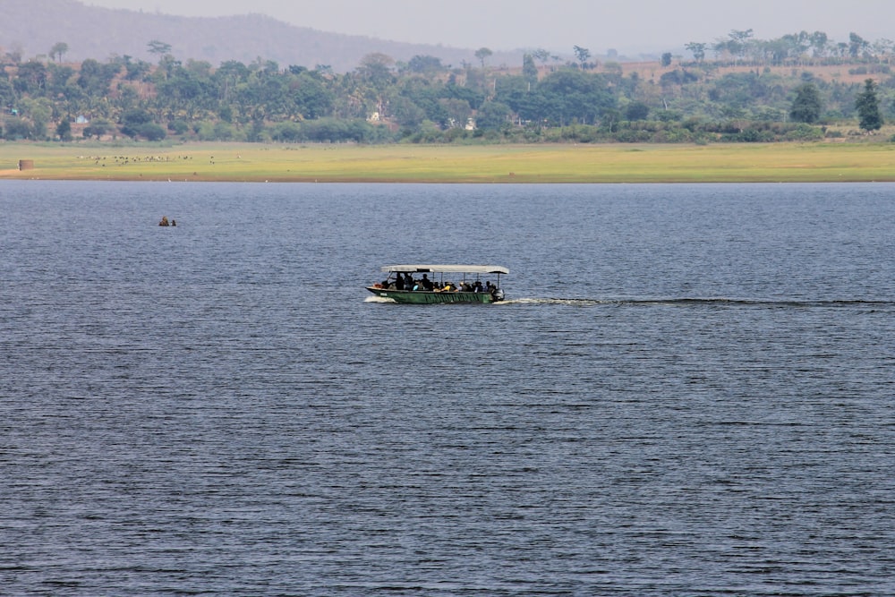 people in boat on body of water viewing mountain during daytime