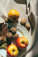 A vibrant display of fresh apples, ginger, mandarins, cashew nuts, basmati rice, and walnuts arranged on a rustic wooden table.