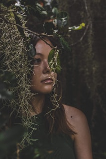 Close-up portrait of a young woman with natural light filtering through forest leaves