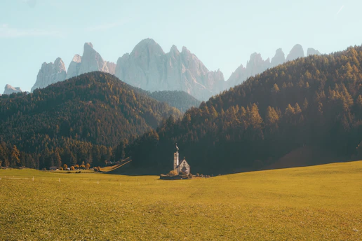 A warm, inviting photo of one of the seven village churches bathed in soft morning light, surrounded by green fields.