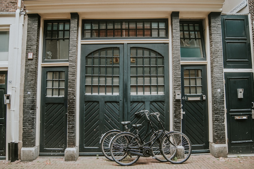 two black bicycles in front of a green door