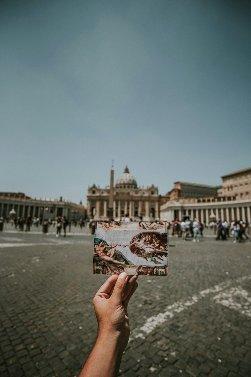 person holding a photo of Creation of Adam painting