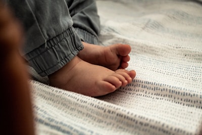 Close-up of a woman’s feet wearing soft pastel sloth socks on a cozy rug.