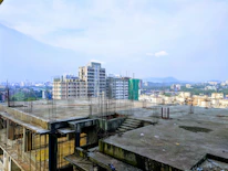 Architect reviewing blueprints on a construction site with a city skyline backdrop.