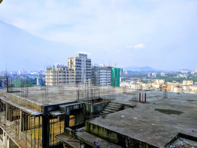 Architect reviewing blueprints on a construction site with a city skyline backdrop.